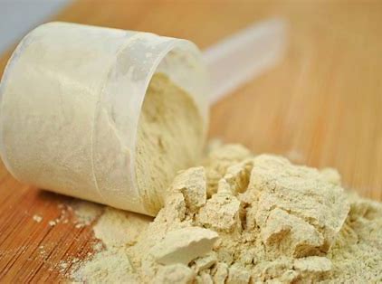 A scoop of whey protein powder on a table.